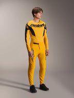 Modelo a usar a camisola Alpinestars Limited Edition A-Supra Melt Gold, camisola de MTB de manga comprida em amarelo escuro e preto, combinada com calças amarelas a condizer e sapatos pretos, equipamento técnico de ciclismo todo-o-terreno com gráficos inspirados na competição