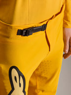 Alpinestars Limited Edition A-Supra Melt Gold Pants, calças de BTT, amarelo escuro, grande plano do sistema de fecho de catraca preto na cintura, com perfurações a laser na parte interna da coxa para ventilação