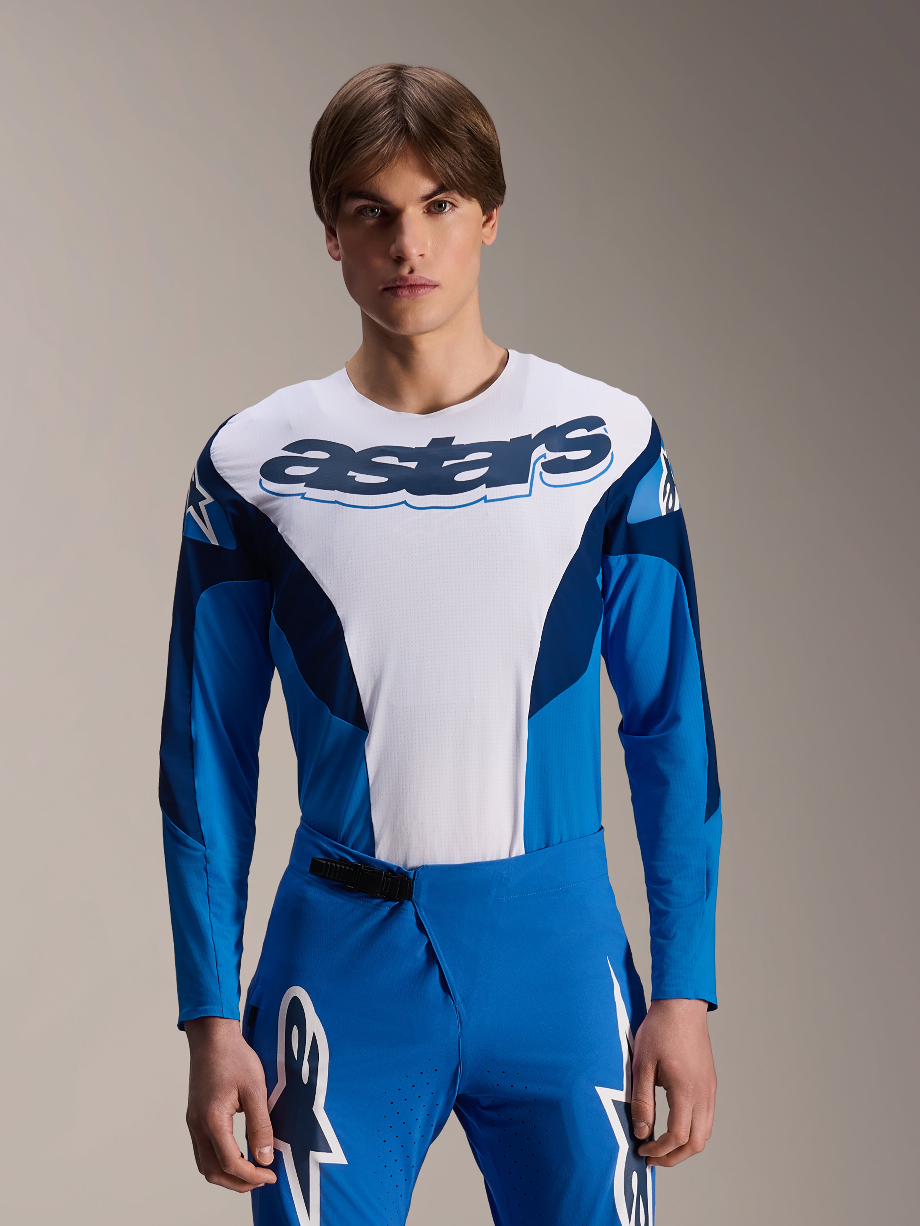 Camisola de manga comprida Alpinestars A-Supra Melt, camisola de MTB azul e branca, com logótipo astars em destaque no peito, mangas azul-escuras, calças de corrida azuis a condizer com logótipos de estrelas brancos, equipamento de mountain bike de alta performance