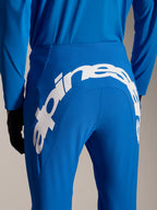 Calças e Camisola Alpinestars A-Supra Melt, equipamento de MTB azul, vista traseira com grande logótipo Alpinestars em branco na pala traseira das calças, camisola de manga comprida a condizer e luvas pretas