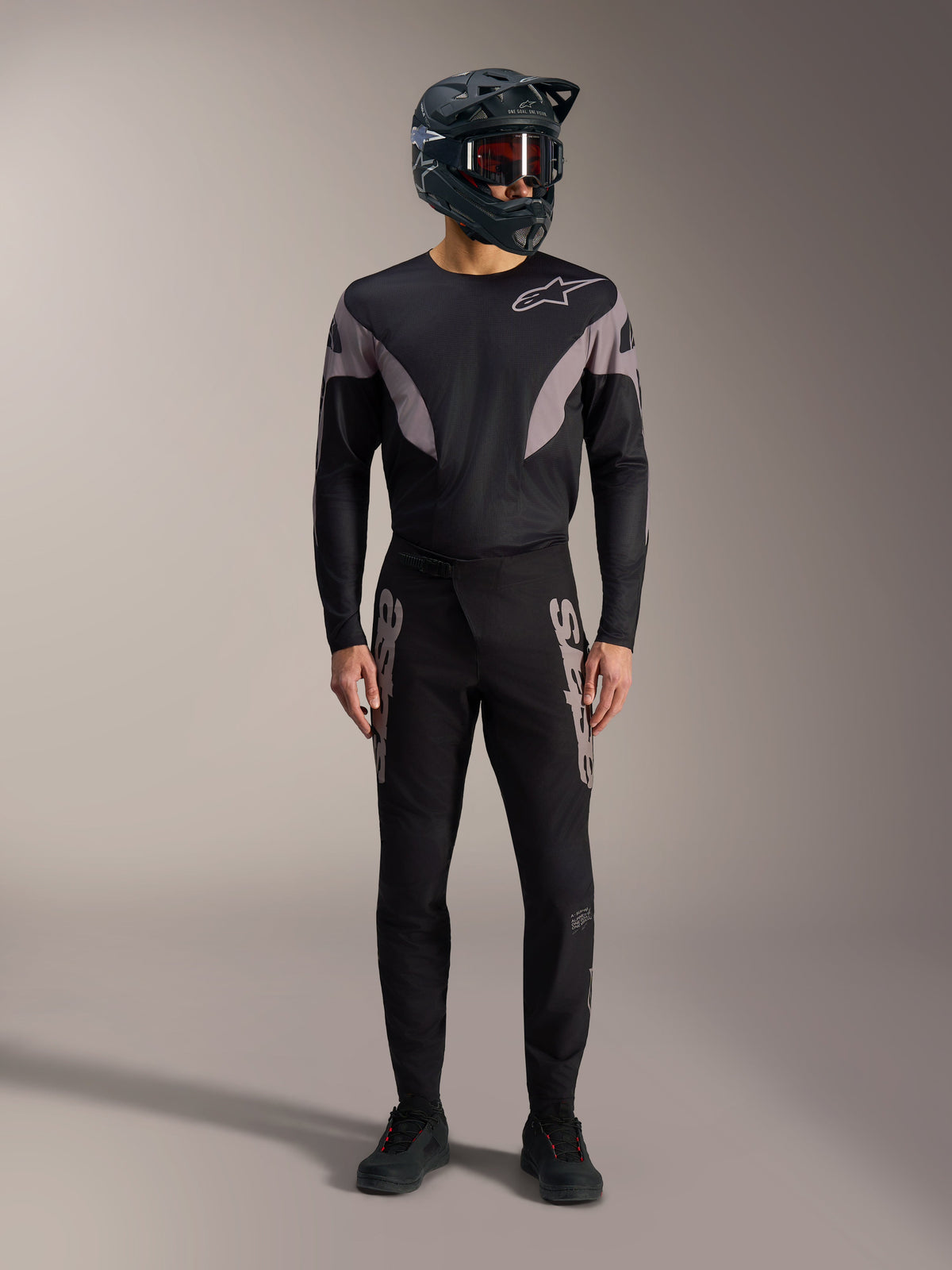 Kit de BTT A-Supra Elite preto, camisola de manga comprida e calças com logótipos cinzentos e capacete integral.
