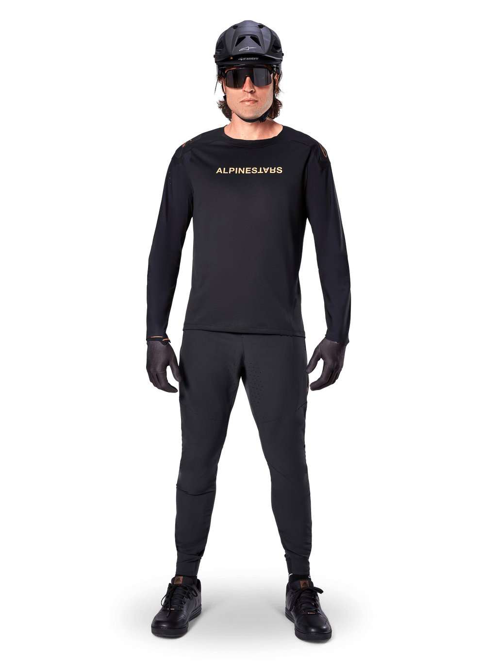 Alpinestars A-Aria Polartec Switch Long Sleeve Jersey, preto, usado por um ciclista com calças técnicas pretas a condizer, capacete preto, óculos de sol e luvas pretas, equipamento de performance de BTT para trilhos fora de estrada