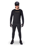 Alpinestars A-Aria Polartec Switch Long Sleeve Jersey, preto, usado por um ciclista com calças técnicas pretas a condizer, capacete preto, óculos de sol e luvas pretas, equipamento de performance de BTT para trilhos fora de estrada