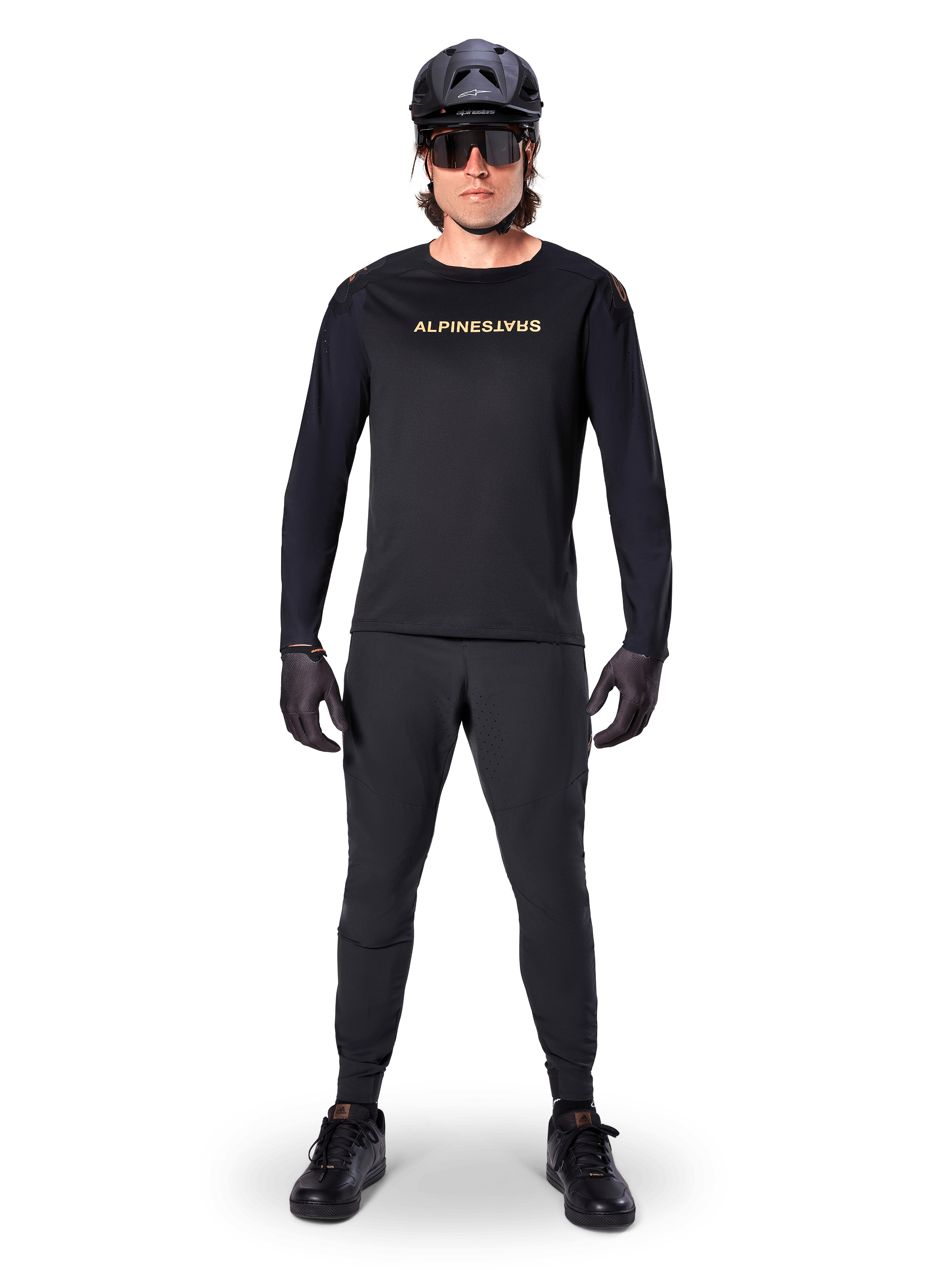 Alpinestars A-Aria Polartec Switch Long Sleeve Jersey, preto, usado por um ciclista com calças técnicas pretas a condizer, capacete preto, óculos de sol e luvas pretas, equipamento de performance de BTT para trilhos fora de estrada