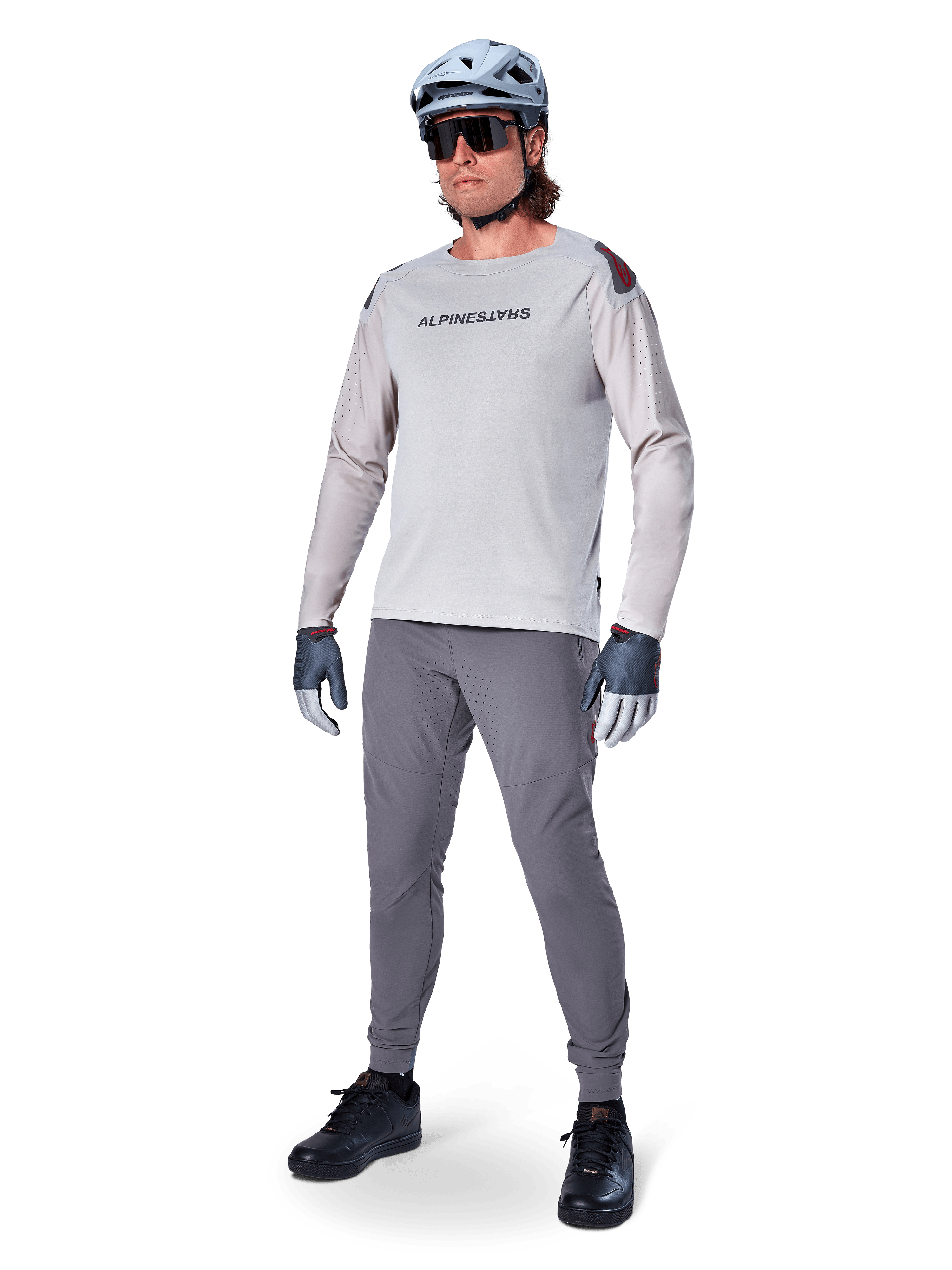 Alpinestars A-Aria Polartec Switch Jersey, Long Sleeve MTB Jersey, Light Gray, worn with dark gray mountain bike pants, helmet, and gloves, featuring laser-perforated sleeves and Alpinestars branding on the chest.