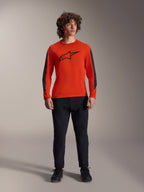 Camisola Alpinestars A-Dura Insert Astar - Manga Comprida, Spicy Orange com logótipo Astar preto e painéis cinzento escuro nas mangas, usada com calças e sapatos de mountain bike pretos, construção têxtil durável para condução fora de estrada