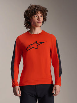 Alpinestars A-Dura Insert Astar Jersey de manga comprida, cor laranja Spicy Orange com logótipo Astar preto, inserções duráveis cinzento-escuro nas mangas, vestida por um modelo masculino, equipamento de performance para ciclismo de montanha (MTB)