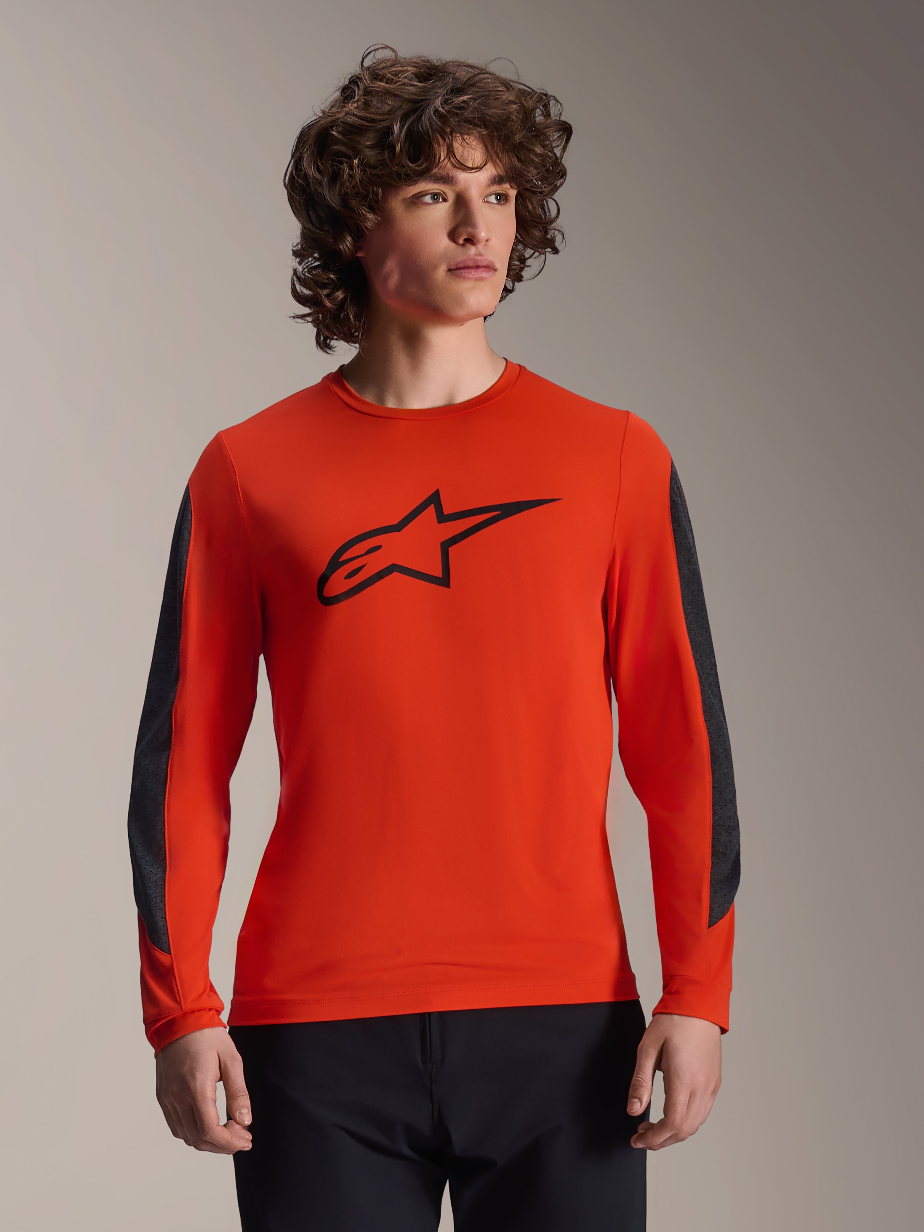 Alpinestars A-Dura Insert Astar Jersey de manga comprida, cor laranja Spicy Orange com logótipo Astar preto, inserções duráveis cinzento-escuro nas mangas, vestida por um modelo masculino, equipamento de performance para ciclismo de montanha (MTB)