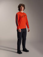 Modelo masculino a usar a camisola de manga comprida Alpinestars A-Dura Insert Astar, cor Spicy Orange com logótipo Astar preto no peito, inserções cinzentas escuras nas mangas, combinada com calças pretas, equipamento profissional de ciclismo MTB