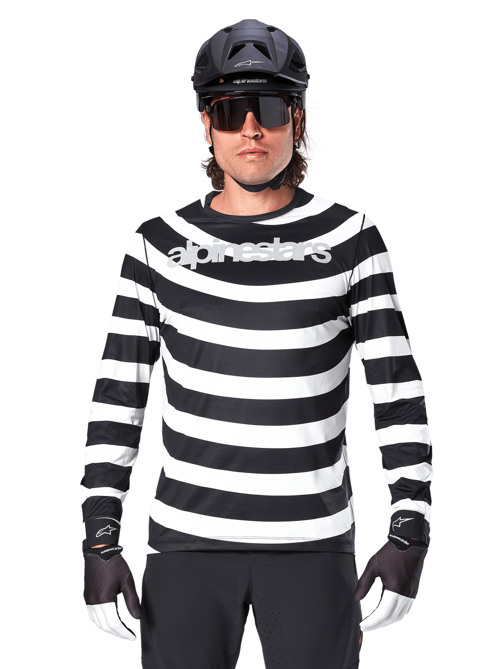 Ciclista masculino com Jersey de Manga Comprida Alpinestars A-Aria Oscar, listas horizontais pretas e brancas, logótipo Alpinestars refletor no peito, combinado com capacete de MTB preto, óculos de sol de ciclismo e luvas de performance