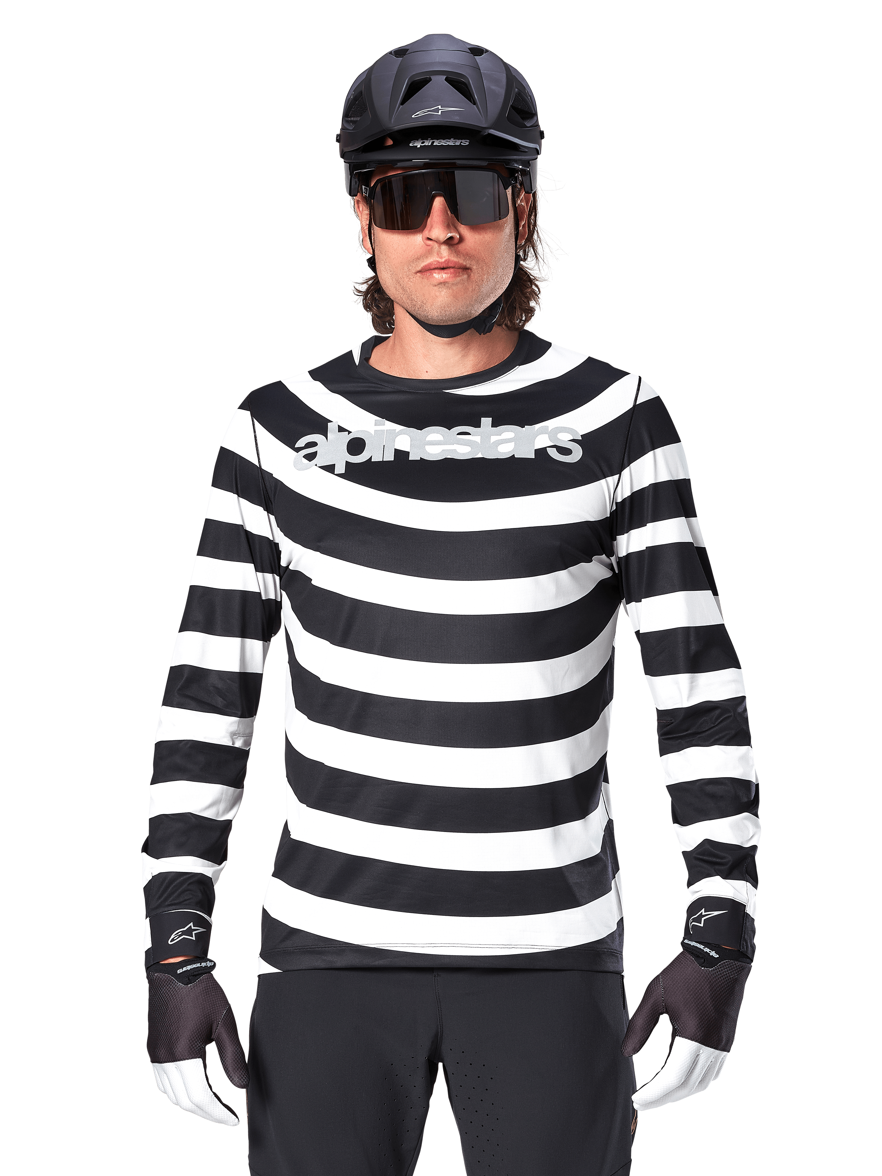 Ciclista masculino com Jersey de Manga Comprida Alpinestars A-Aria Oscar, listas horizontais pretas e brancas, logótipo Alpinestars refletor no peito, combinado com capacete de MTB preto, óculos de sol de ciclismo e luvas de performance