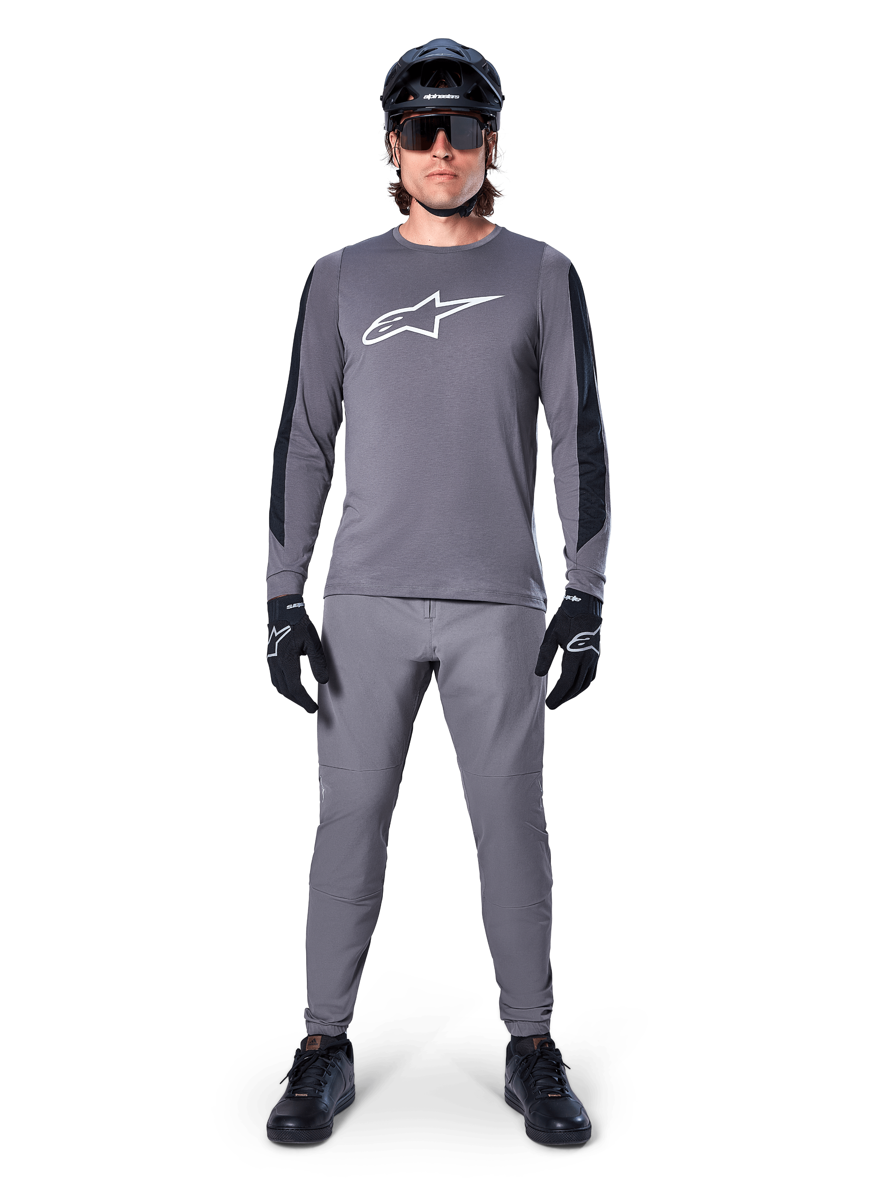Alpinestars A-Dura Dri Astar Jersey, Long Sleeve MTB Jersey in Dark Gray, featuring a white chest logo and black sleeve panels, worn with matching gray pants, black helmet, sunglasses, and gloves for a complete off-road cycling outfit
