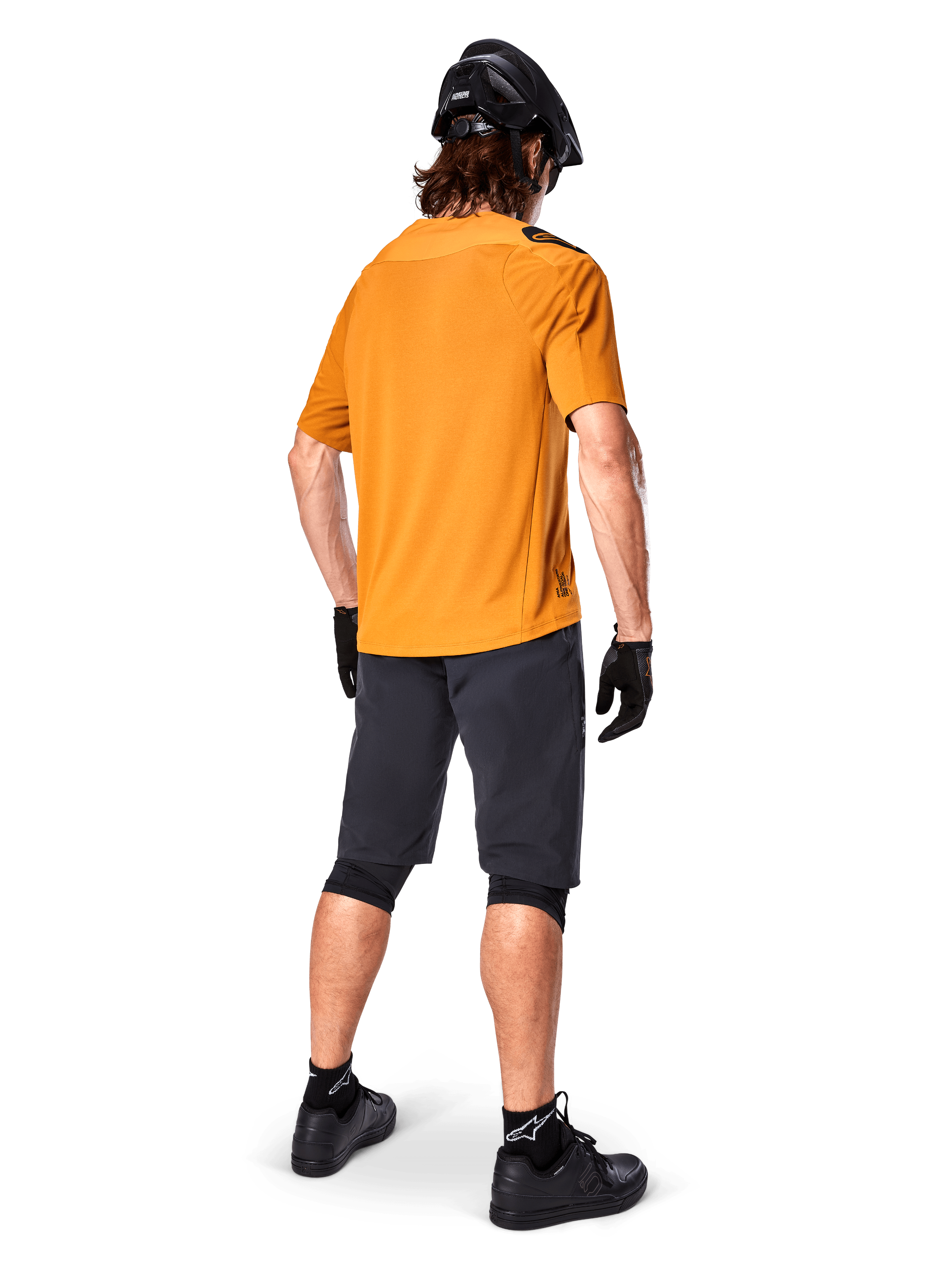 Alpinestars A-Aria Polartec Switch Jersey, camisola de BTT de manga curta, amarela, vista traseira de modelo a usar calções de BTT cinzento escuro, capacete preto e luvas, vestuário técnico de ciclismo para trilhos fora de estrada