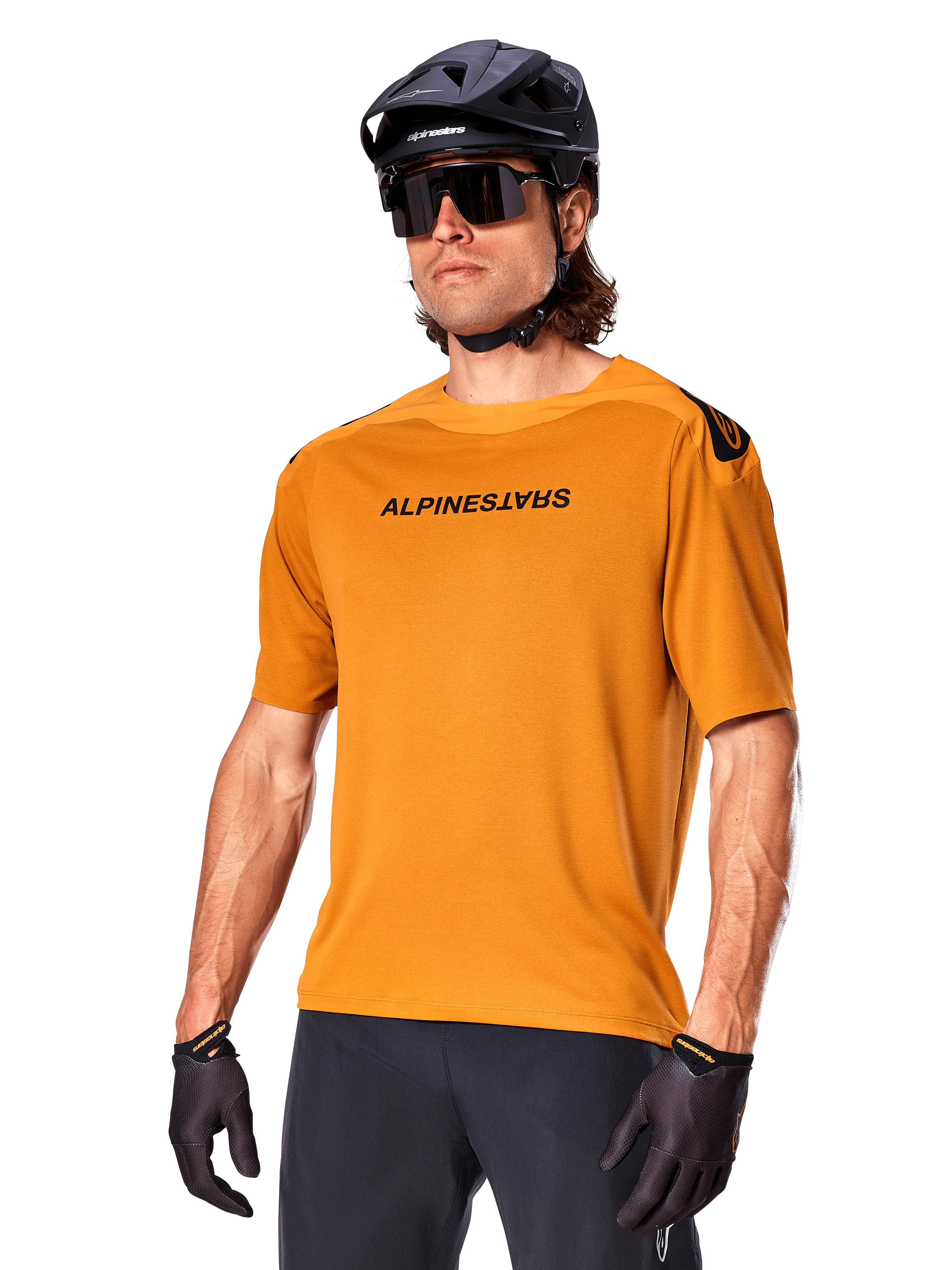 Alpinestars A-Aria Polartec Switch Jersey, camisola de BTT de manga curta, Dark Gold com logótipo preto, usada por um modelo com capacete preto, óculos de sol e luvas de ciclismo, vestuário de BTT de alta performance