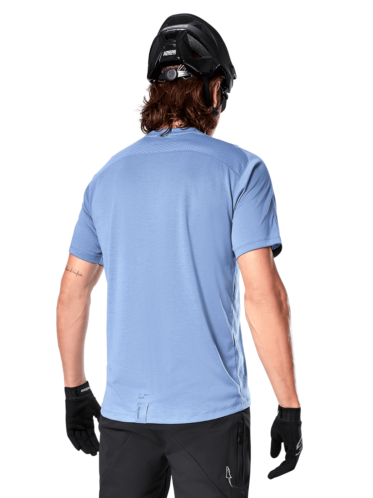 Alpinestars Camisola A-Dura Dri Astar de Manga Curta, camisola de BTT, Azul Infinity, vista traseira com painéis de ventilação em malha nos ombros e cauda alongada, acompanhada por capacete de BTT e luvas pretas, equipamento de ciclismo de alta performance