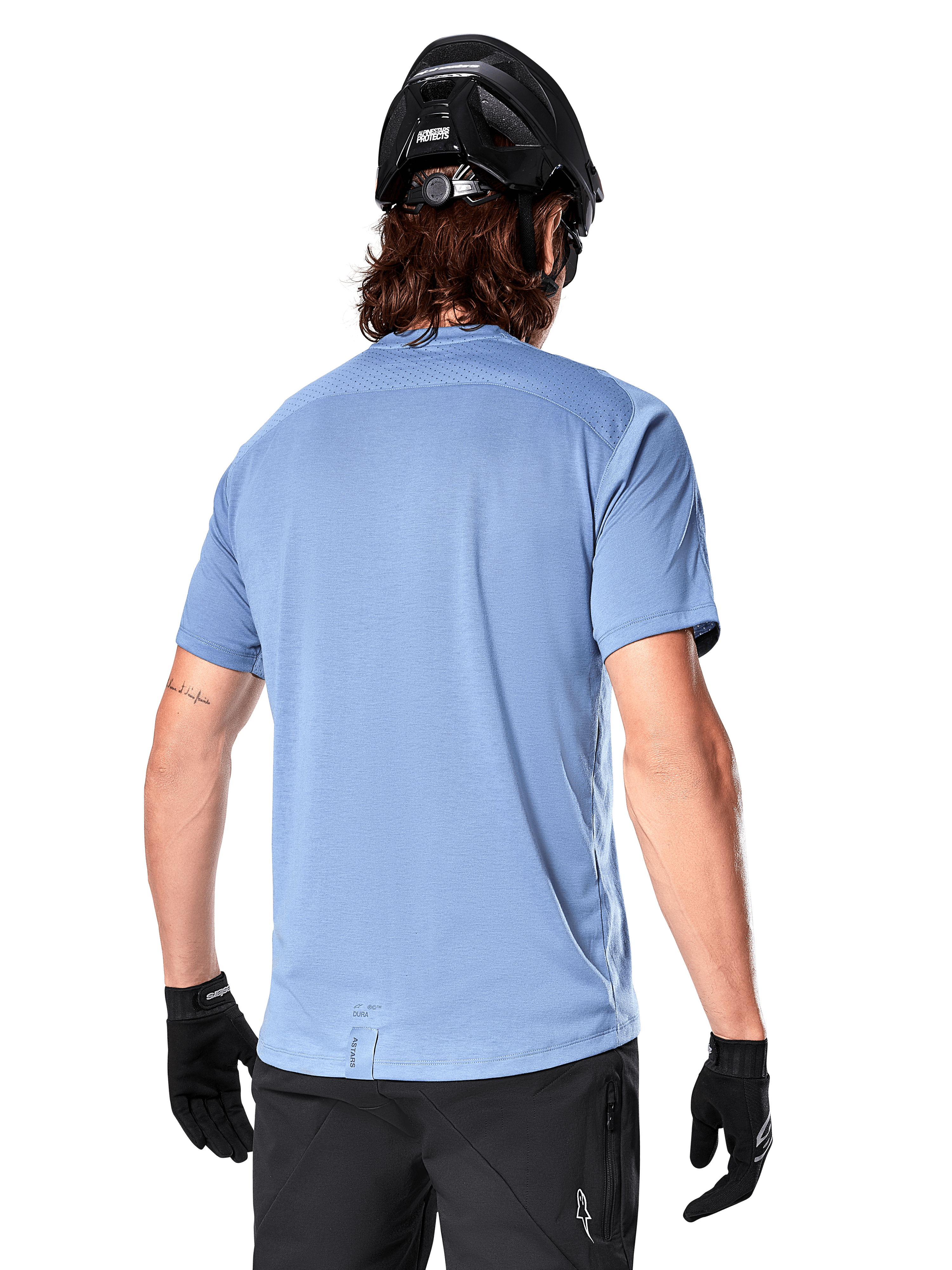 Alpinestars A-Dura Dri Astar Short Sleeve Jersey, MTB Jersey, Infinity Blue, back view showing mesh ventilation panels on shoulders and a longer drop tail, worn with a black MTB helmet and gloves, performance cycling gear