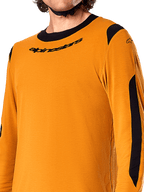 Camisola de manga comprida Alpinestars A-Dura Dri Wool, Dark Gold, pormenor da gola redonda preta com logótipo e painéis de ventilação em malha preta nos ombros e braços, vestuário de BTT de alta performance