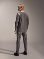 Male model wearing Alpinestars A-Dura Dri Wool Long Sleeve Jersey, Dark Gray with light gray mesh shoulder panels, paired with matching dark gray cycling pants, back view showing the drop tail hem, mountain bike apparel