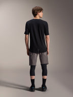 Calções Alpinestars A-Dura Elite, calções de mountain bike cinzento-escuros, vista traseira, usados com uma camisola preta de manga curta, joelheiras e meias pretas, equipamento técnico de ciclismo para condução off-road
