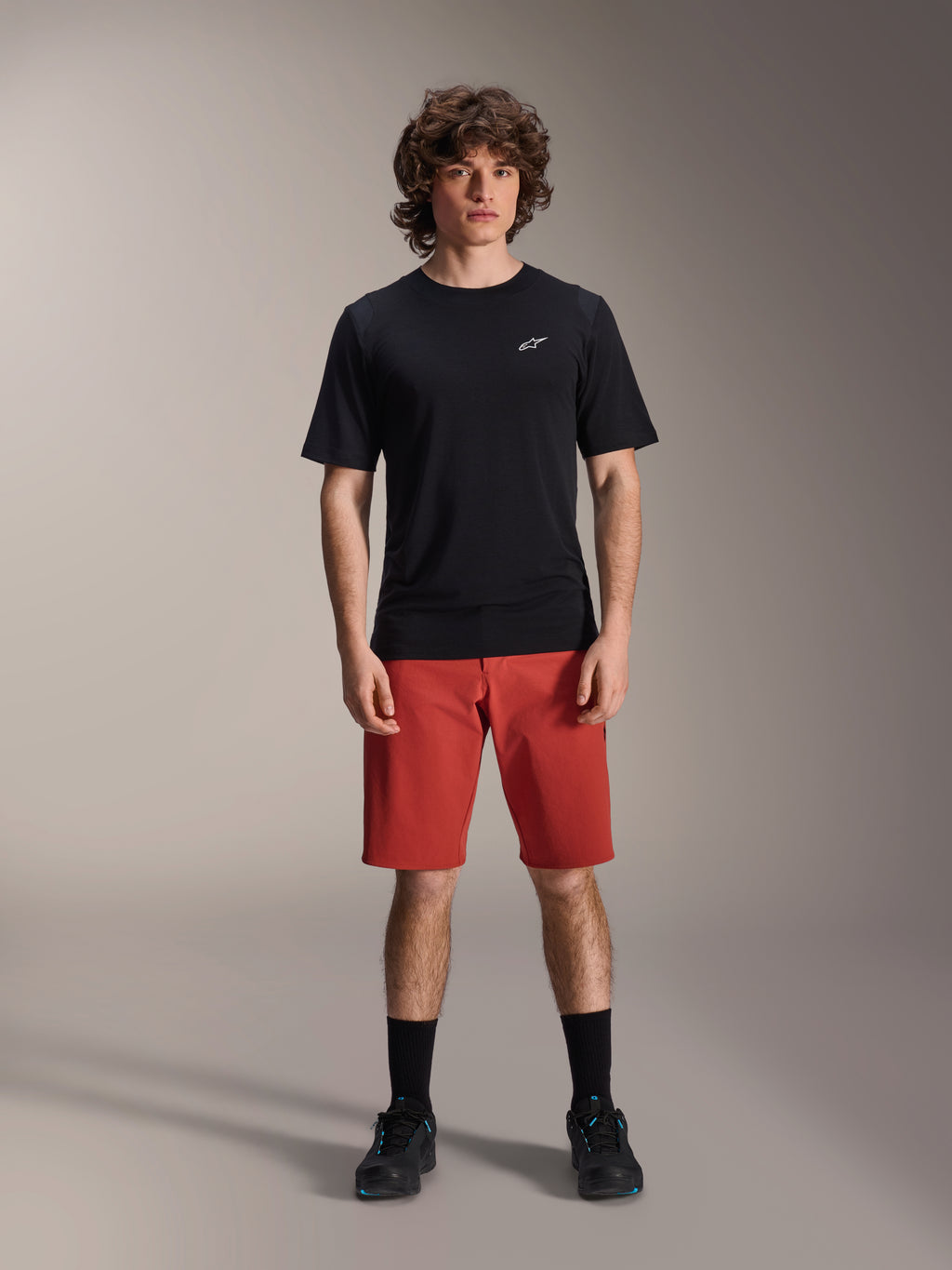 Alpinestars A-Dura Elite Shorts, calções de BTT, laranja escuro, usados com uma camisola de manga curta preta e sapatilhas de ciclismo, vestuário de ciclismo de performance para BTT