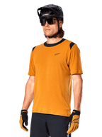 Alpinestars A-Dura Dri Wool Jersey - Manga Curta, camisola de ciclismo MTB, ouro escuro com detalhes pretos, camisola técnica de manga curta em mistura de lã com painéis pretos nos ombros, usada com capacete de MTB preto e luvas a condizer