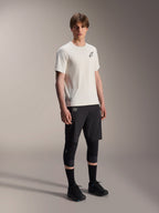 Camisola Alpinestars A-Aria Astar, Manga Curta, Ecru, com logótipo preto no peito, usada com calções de ciclismo pretos e joelheiras, equipamento de performance leve para MTB