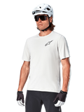 Camisola de manga curta Alpinestars A-Aria Astar, White Dove, vestida por um ciclista com capacete branco e óculos de sol escuros, com um pequeno logótipo de estrela preto no peito, equipamento de performance respirável para BTT
