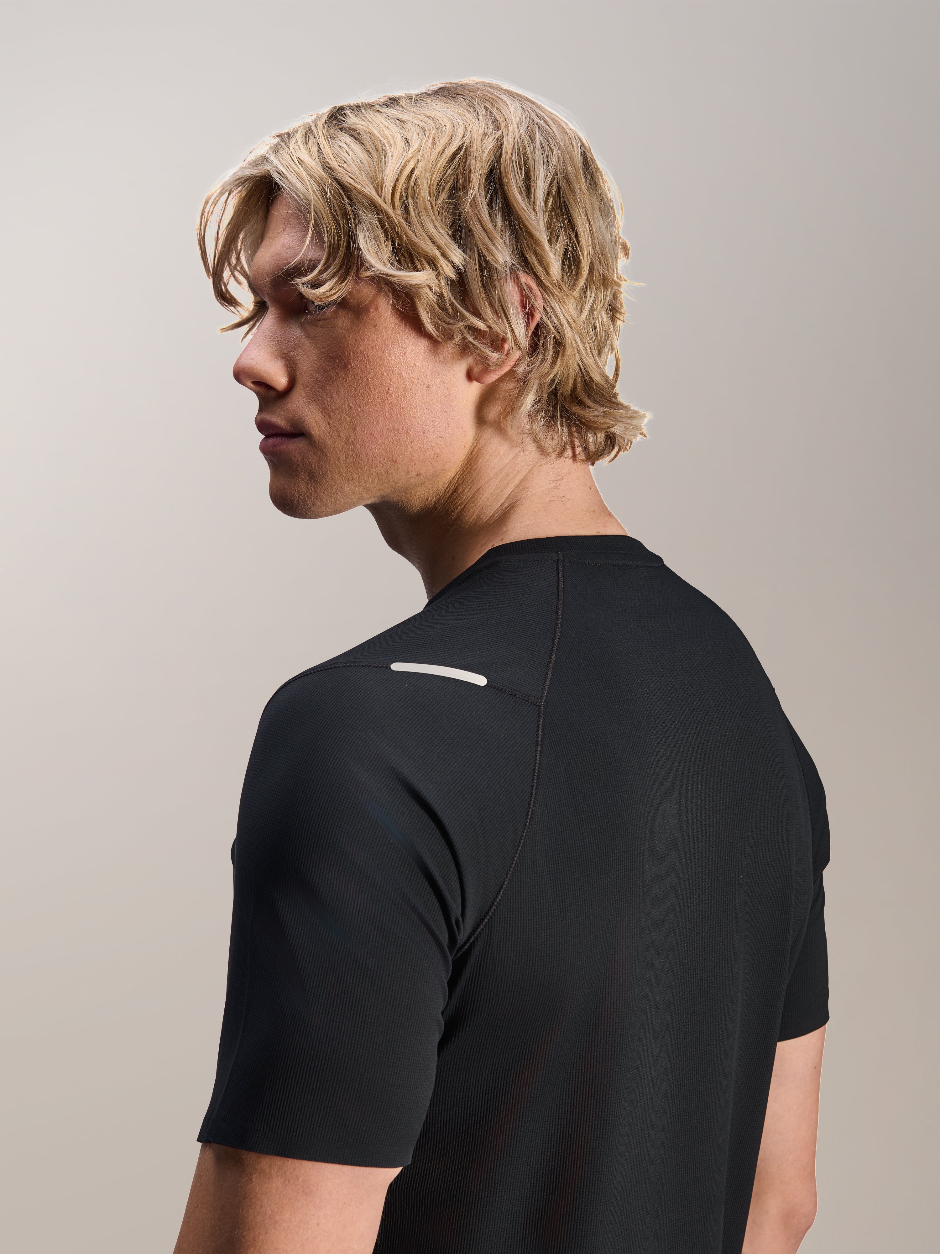 Homem a usar a Camisola Alpinestars A-Aria Switch, Manga Curta, Preta, vista lateral e traseira mostrando o ajuste de performance e pormenores no ombro, vestuário de ciclismo BTT leve e respirável