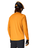 Camisola de Manga Comprida Alpinestars A-Dura Rocker, Dark Gold, vista traseira de ciclista com capacete de BTT preto e laranja, calças escuras e luvas a combinar, vestuário casual de performance para bicicleta de montanha