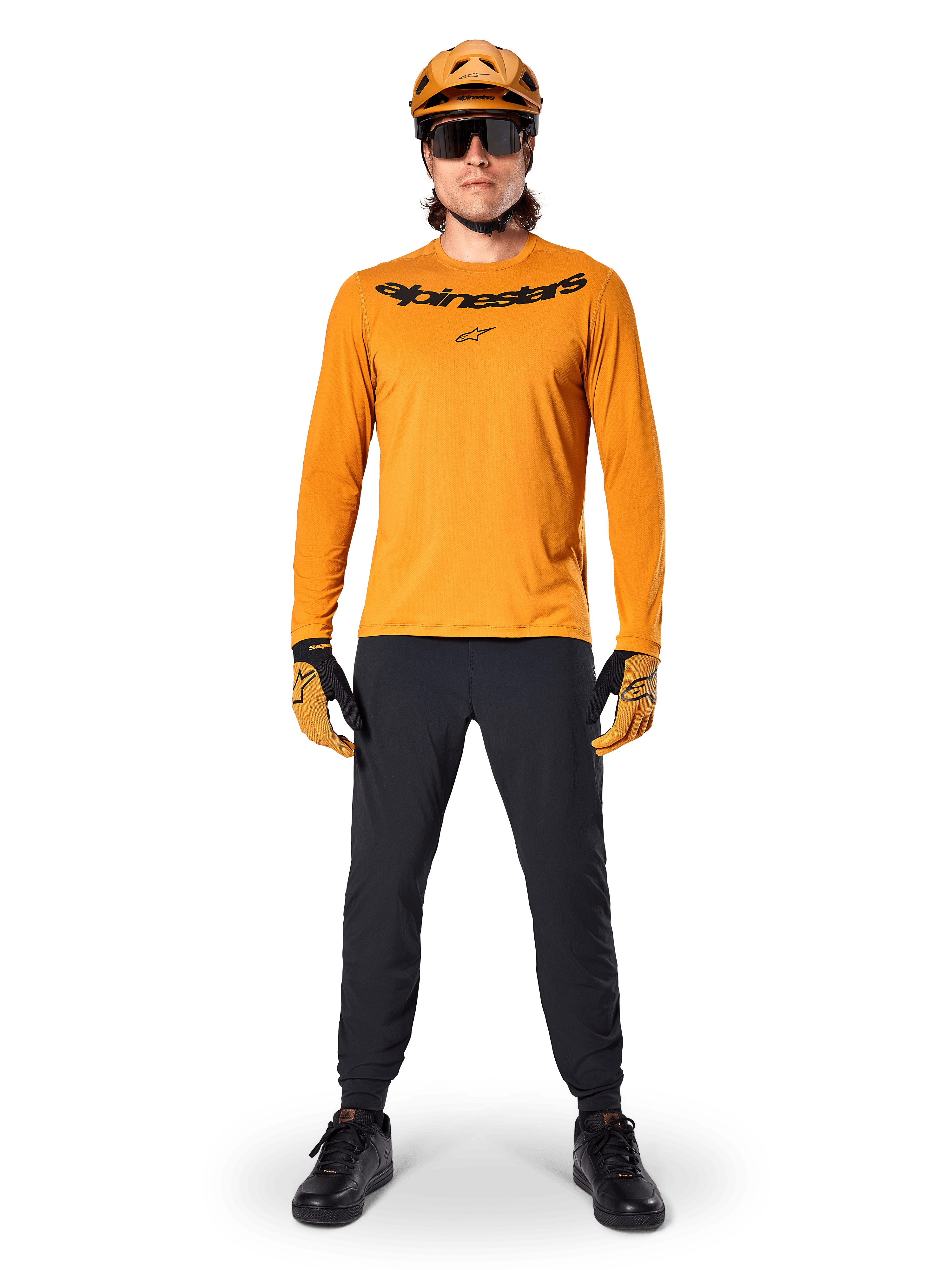 Camisola de Manga Longa Alpinestars A-Dura Rocker em Dark Gold, com logótipo preto impresso no peito, usada com um capacete de BTT dourado a condizer, óculos de sol pretos e calças pretas, equipamento profissional de mountain bike