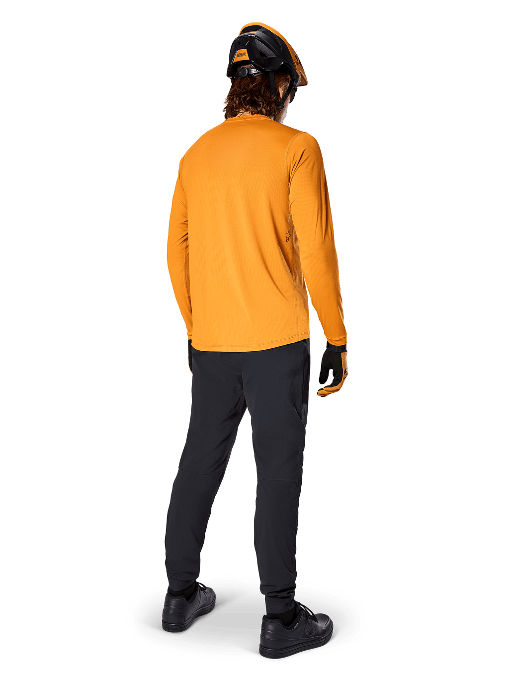 Ciclista de BTT visto de costas a usar a Camisola de Manga Comprida Alpinestars A-Dura Rocker em Dark Gold, calças pretas, capacete laranja e preto e sapatos pretos, equipamento técnico de BTT para trilhos