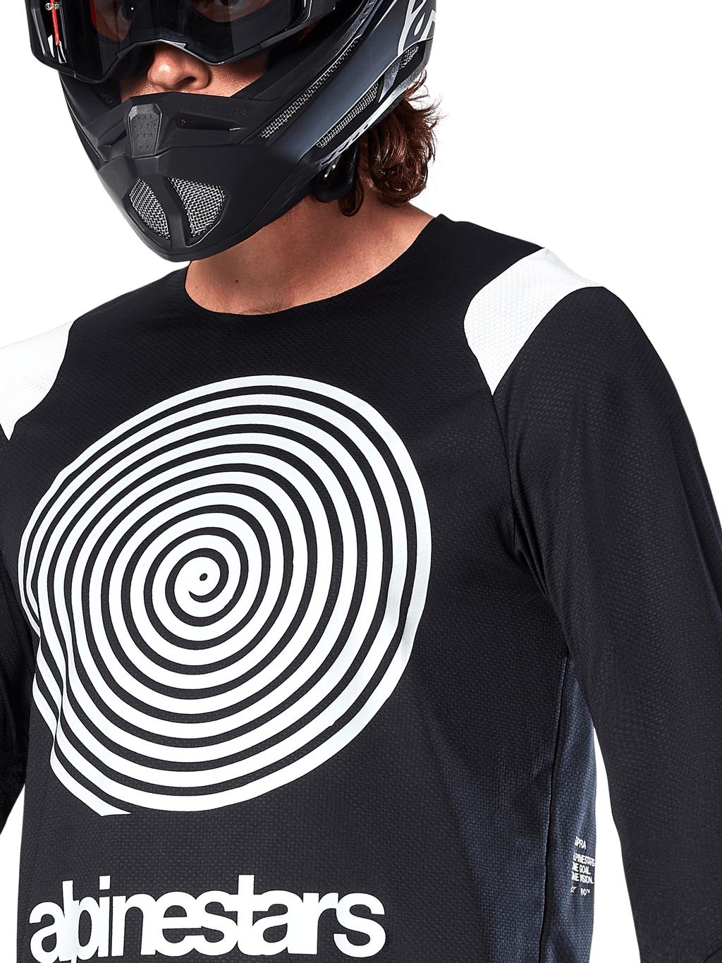 Camisola Alpinestars A-Supra Oscar, de manga comprida, preta, com um grande gráfico em espiral Oscar branco no peito e o logótipo da marca, usada por um ciclista com capacete integral preto e óculos de proteção, vestuário de BTT de performance para modalidades de gravidade