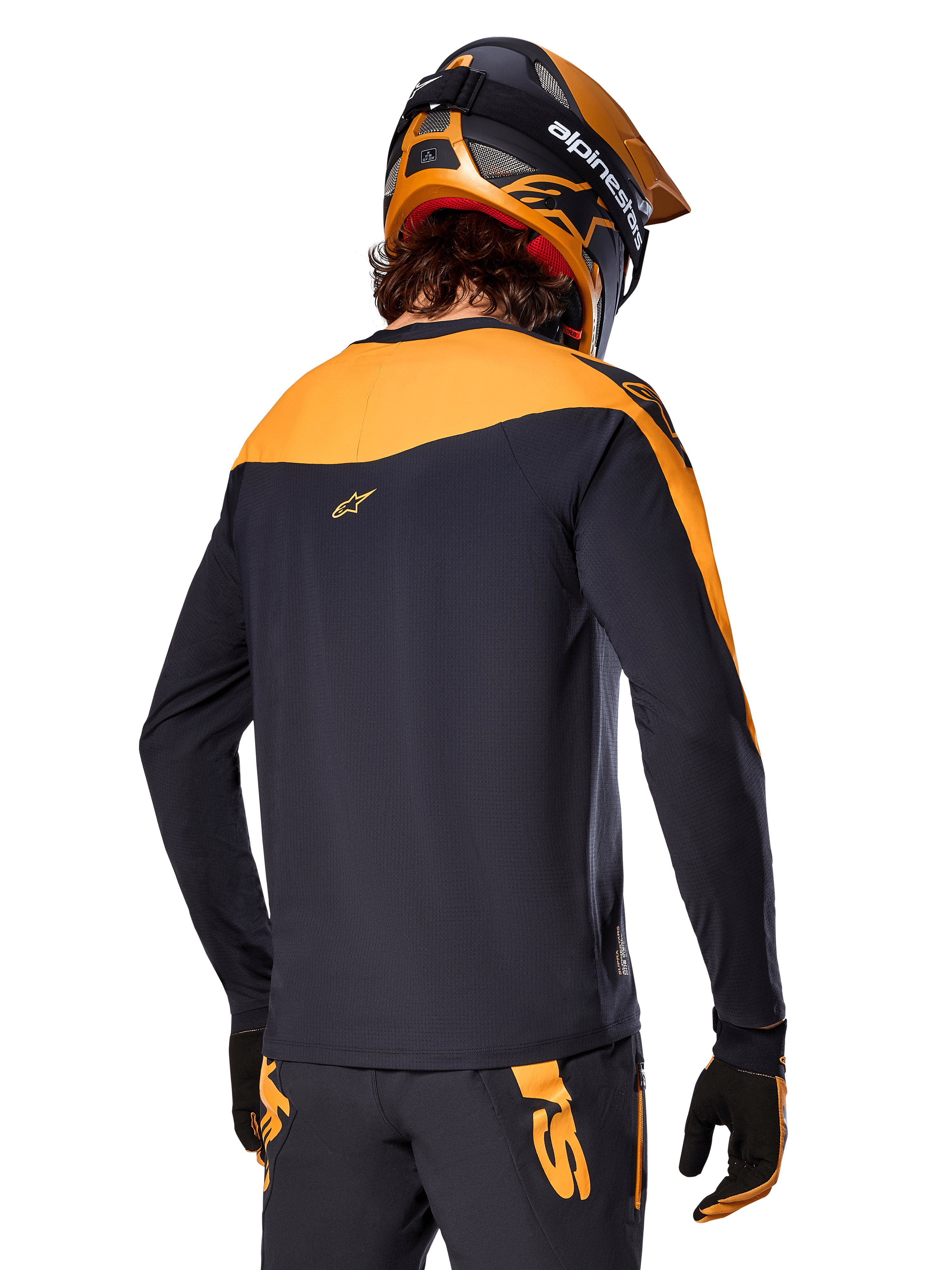 Alpinestars A-Supra Race Jersey - Manga Comprida, preto e laranja, vista traseira de ciclista com capacete e calças de BTT a condizer, ajuste de performance com textura microperfurada, equipamento de corrida profissional de BTT