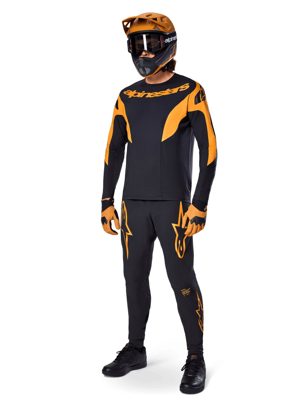 Ciclista de MTB com equipamento de corrida completo, Camisola A-Supra Race preta com detalhes laranja, calças pretas a condizer com logótipos Alpinestars laranja, capacete integral laranja e preto com óculos, luvas laranja e preto, conjunto coordenado para corridas de mountain bike