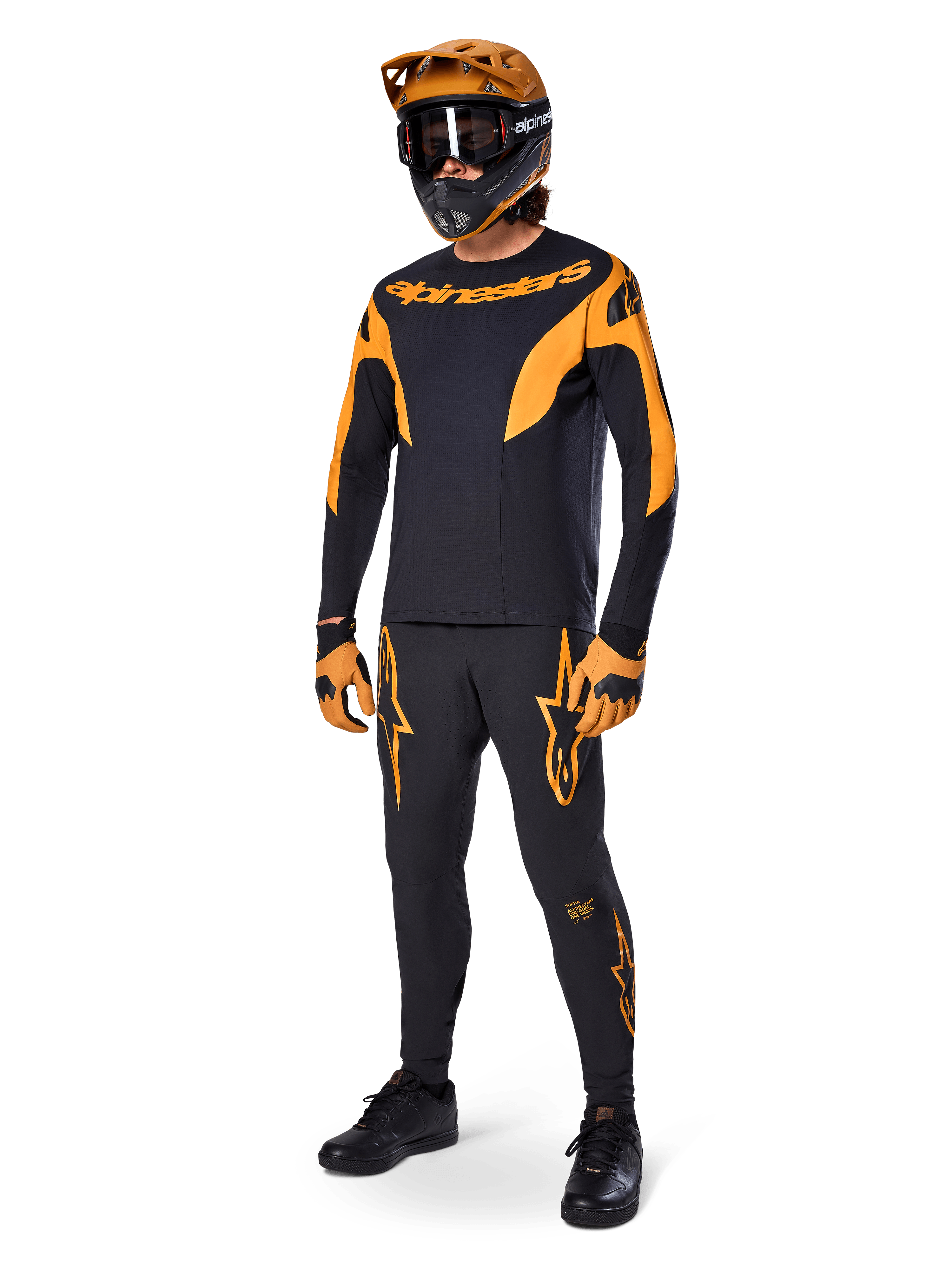 Ciclista de MTB com equipamento de corrida completo, Camisola A-Supra Race preta com detalhes laranja, calças pretas a condizer com logótipos Alpinestars laranja, capacete integral laranja e preto com óculos, luvas laranja e preto, conjunto coordenado para corridas de mountain bike