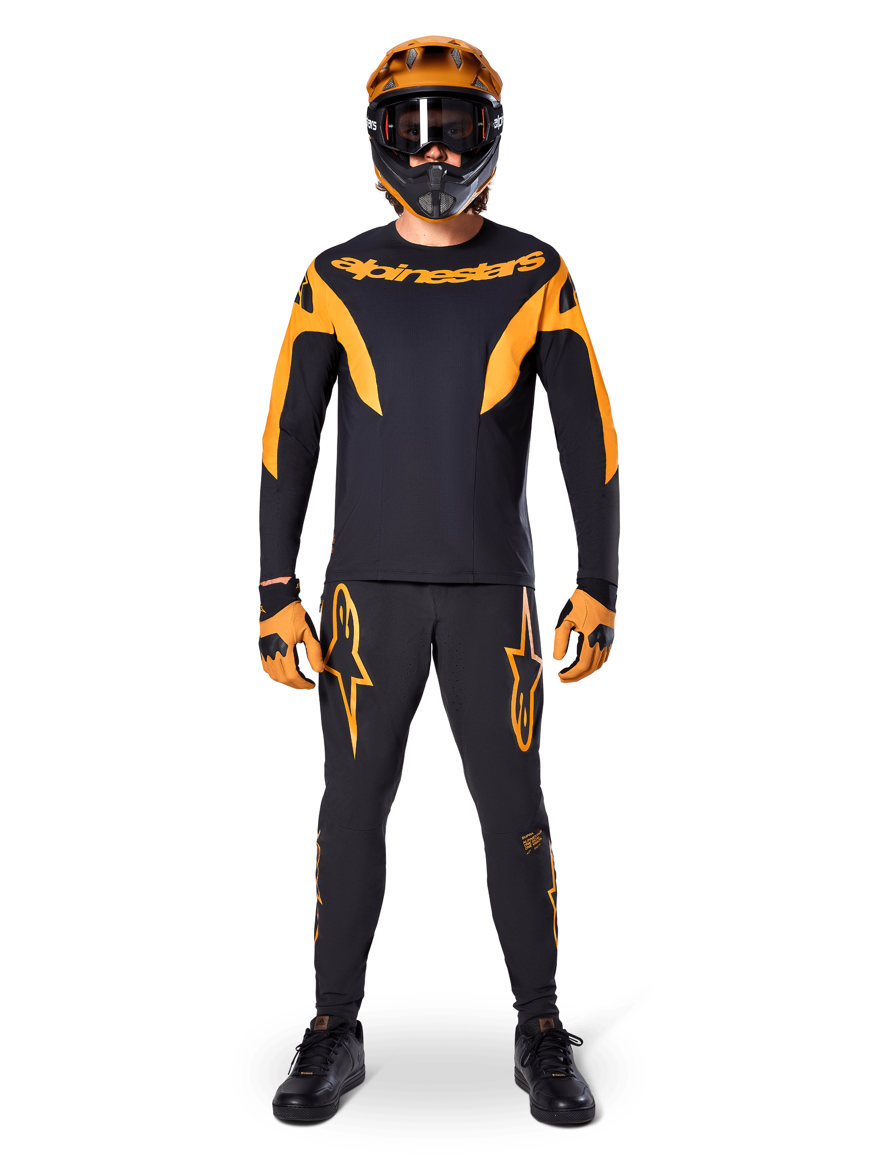 Ciclista de BTT com camisola Alpinestars A-Supra Race - Manga Comprida em preto e laranja, calças, luvas e capacete integral com óculos de proteção a condizer, kit de BTT coordenado para competição e performance fora de estrada