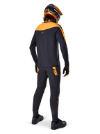 Camisola A-Supra Race - Manga Comprida, preto e laranja, vista traseira de um ciclista com calças de MTB a condizer, capacete e luvas em laranja e preto, equipamento de performance para corridas de mountain bike