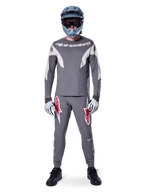 Rider wearing the Alpinestars A-Supra Race Jersey - Long Sleeve in Dark Gray, coordinated with matching gray pants featuring bold red star logos, gray helmet with goggles, and light gray gloves, complete MTB racing kit for performance off-road cycling