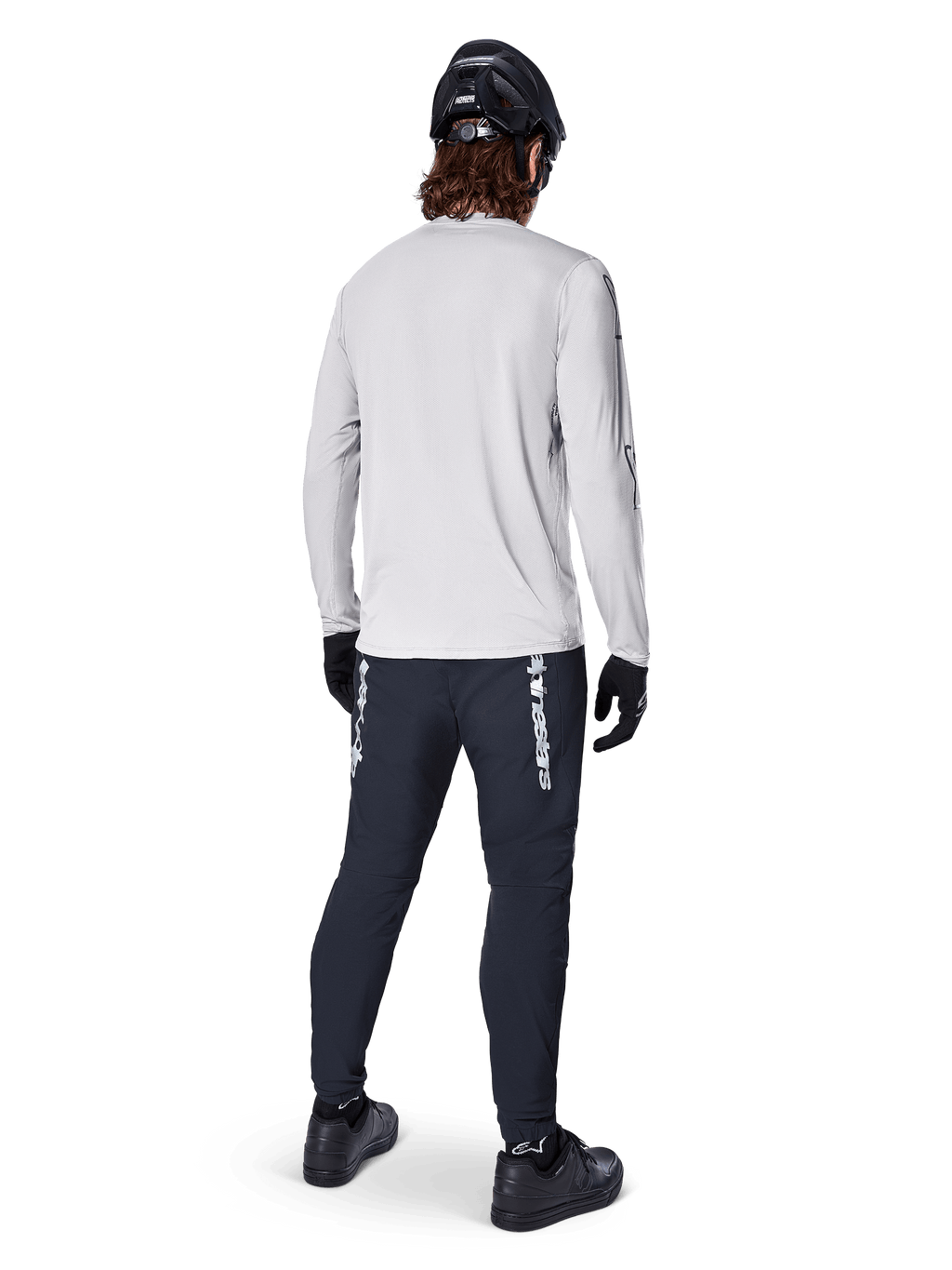 Camisola de Manga Longa Alpinestars A-Dura Switch, Cinzento Claro, vista traseira num ciclista a usar calças de ciclismo pretas, capacete e luvas, equipamento de BTT de alta performance com cauda mais longa.