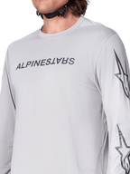 Alpinestars A-Dura Switch Jersey - Manga Comprida, camisola de BTT em cinzento claro com logótipo escrito em cinzento escuro no peito e logótipo de estrela na manga, textura jacquard respirável, equipamento de ciclismo de performance para trilhos