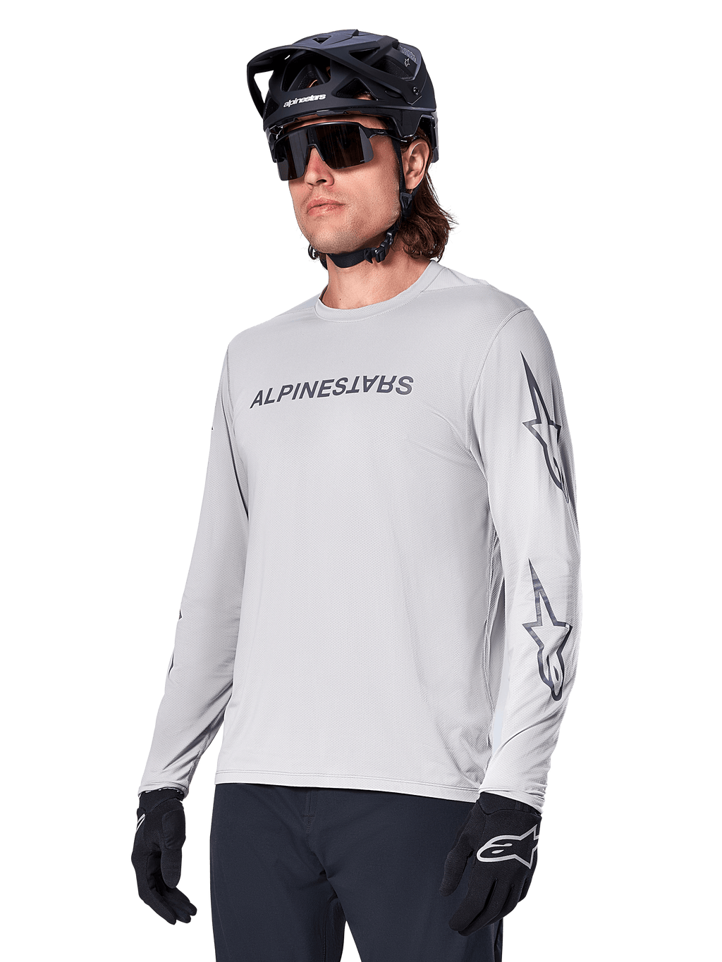 Alpinestars A-Dura Switch Long Sleeve Jersey, camisola de BTT, cinzento claro, logótipo nominativo em serigrafia preta no peito e logótipos de estrela nas mangas, usada com capacete de BTT preto, óculos de sol escuros e luvas pretas, equipamento atlético de ciclismo todo-o-terreno