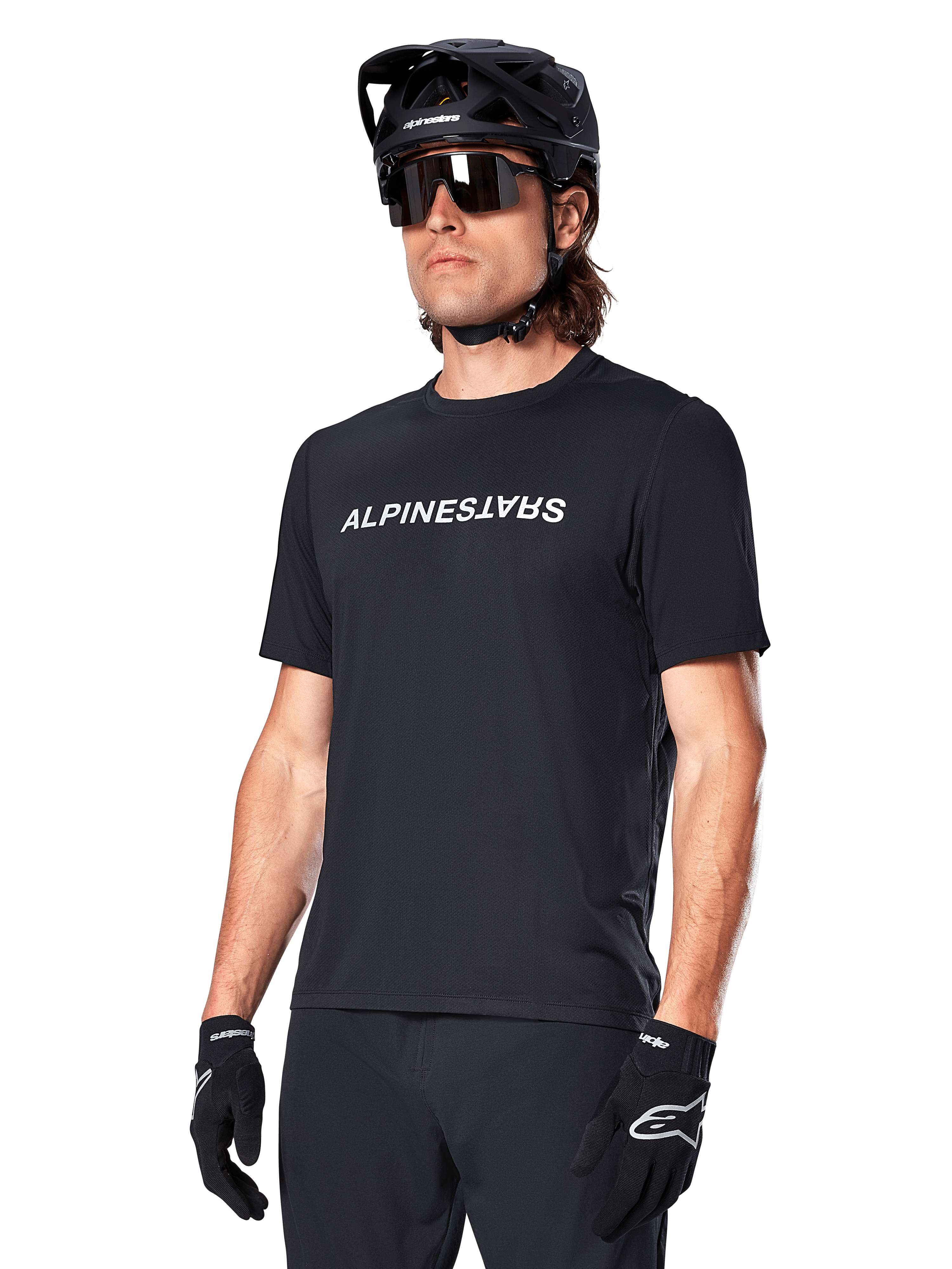 Alpinestars A-Dura Switch Short Sleeve Jersey, preta, com logótipo branco no peito, vestida por um ciclista com capacete de MTB preto e óculos de sol, vestuário técnico concebido para trilhos