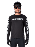 Ciclista masculino com Camisola Alpinestars A-Dura Dri Oscar de Manga Comprida, preto refletor, com logótipo Alpinestars branco no peito e gráficos prateados refletores nas mangas, acompanhado por capacete de BTT preto, óculos de sol e luvas pretas, equipamento de ciclismo de performance