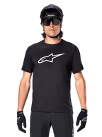 Alpinestars A-Dura Dri Oscar Jersey - Manga Curta, Preto Refletor, usada com capacete de MTB preto, óculos de sol e luvas, apresentando um logótipo branco proeminente no peito, equipamento de performance para mountain bike
