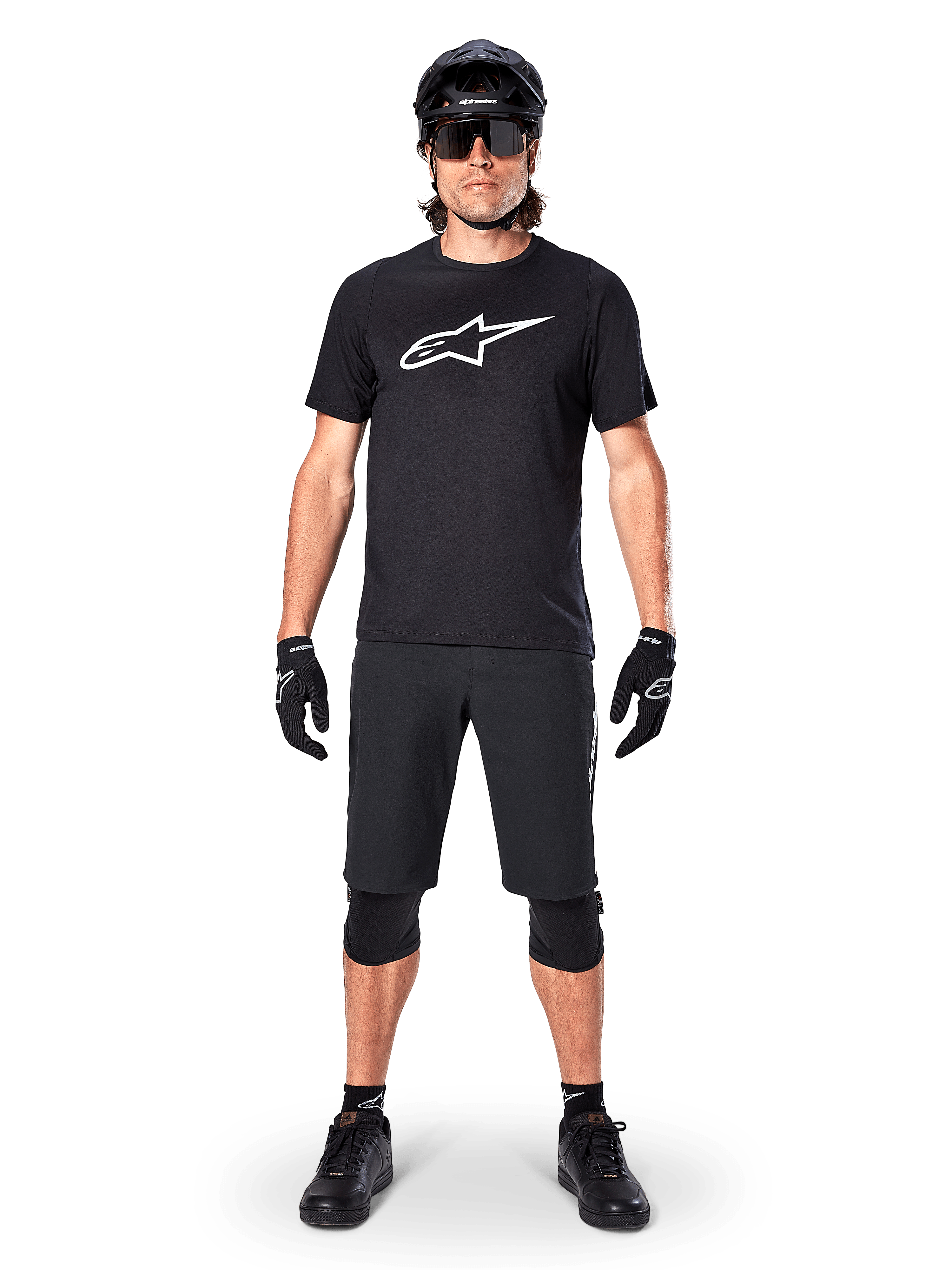 Camisola de Manga Curta Alpinestars A-Dura Dri Oscar, Preto Refletor, usada com calções de BTT pretos a condizer, luvas, joelheiras e capacete, com um logótipo grande da Alpinestars branco no peito, equipamento completo de BTT