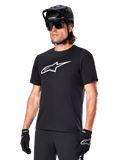 Alpinestars A-Dura Dri Oscar Jersey, camisola de ciclismo BTT de manga curta, preta com logótipo branco, tecido técnico de alto desempenho com gestão de humidade, usada com capacete preto, óculos de sol e luvas