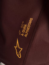 Detail of gold A-Dura Alpinestars branding on bordeaux jacquard fabric of the Stella Ride Long Sleeve MTB jersey.