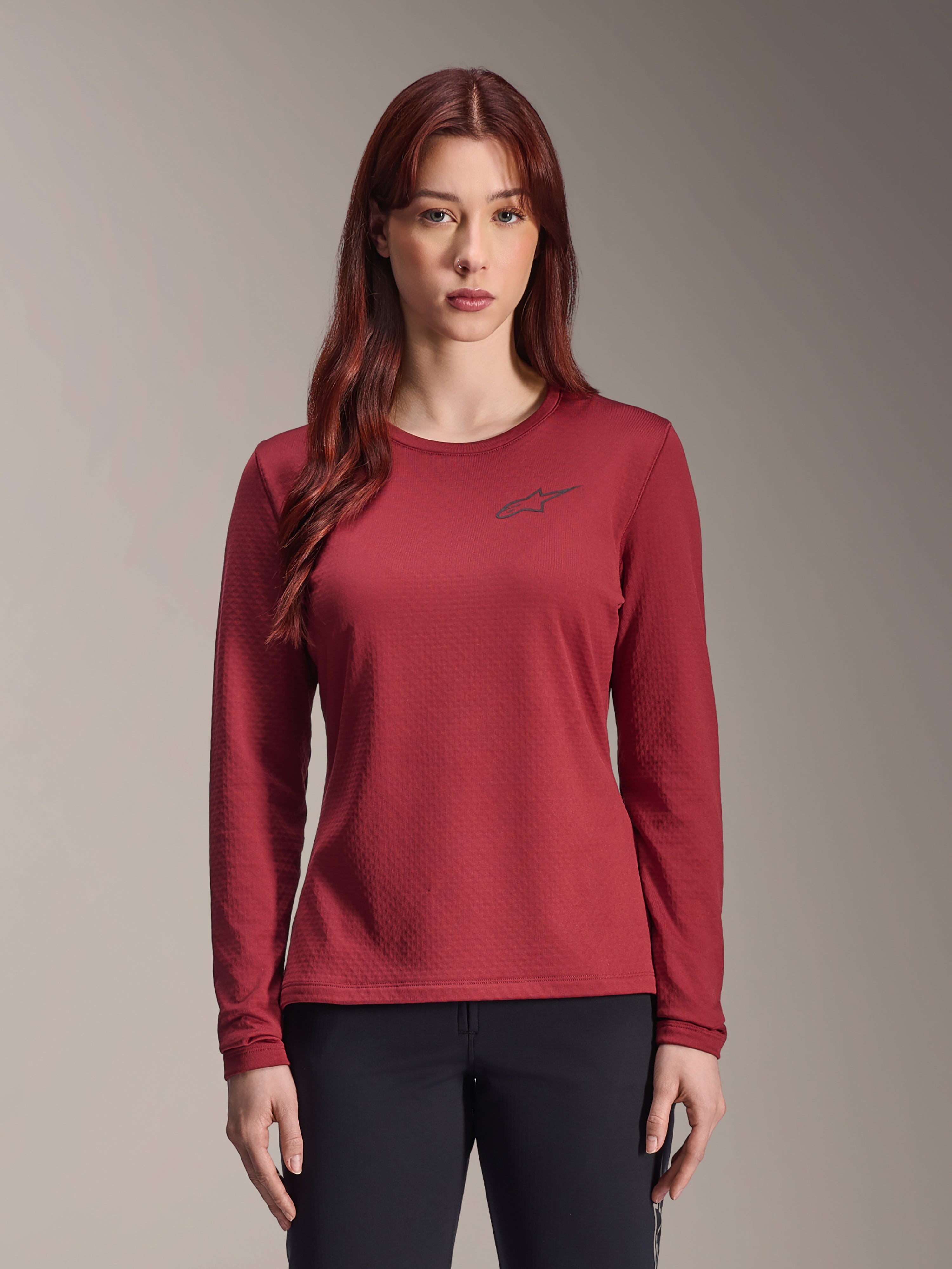 Alpinestars Stella A-Dura Thermal Jersey, camisola de BTT de manga comprida para mulher, cor bordô, tecido térmico texturado, gola redonda com um pequeno logótipo Alpinestars preto no peito, vestida por uma modelo.