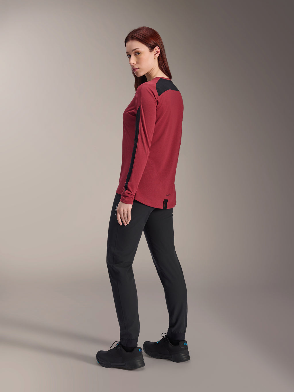 Camisola de Manga Comprida Alpinestars Stella A-Dura Dri Astar para Mulher, bordeaux e preto, usada com calças de BTT pretas e sapatos pretos, vista de perfil posterior, tecido drirelease® reciclado com painéis de malha, vestuário técnico de BTT