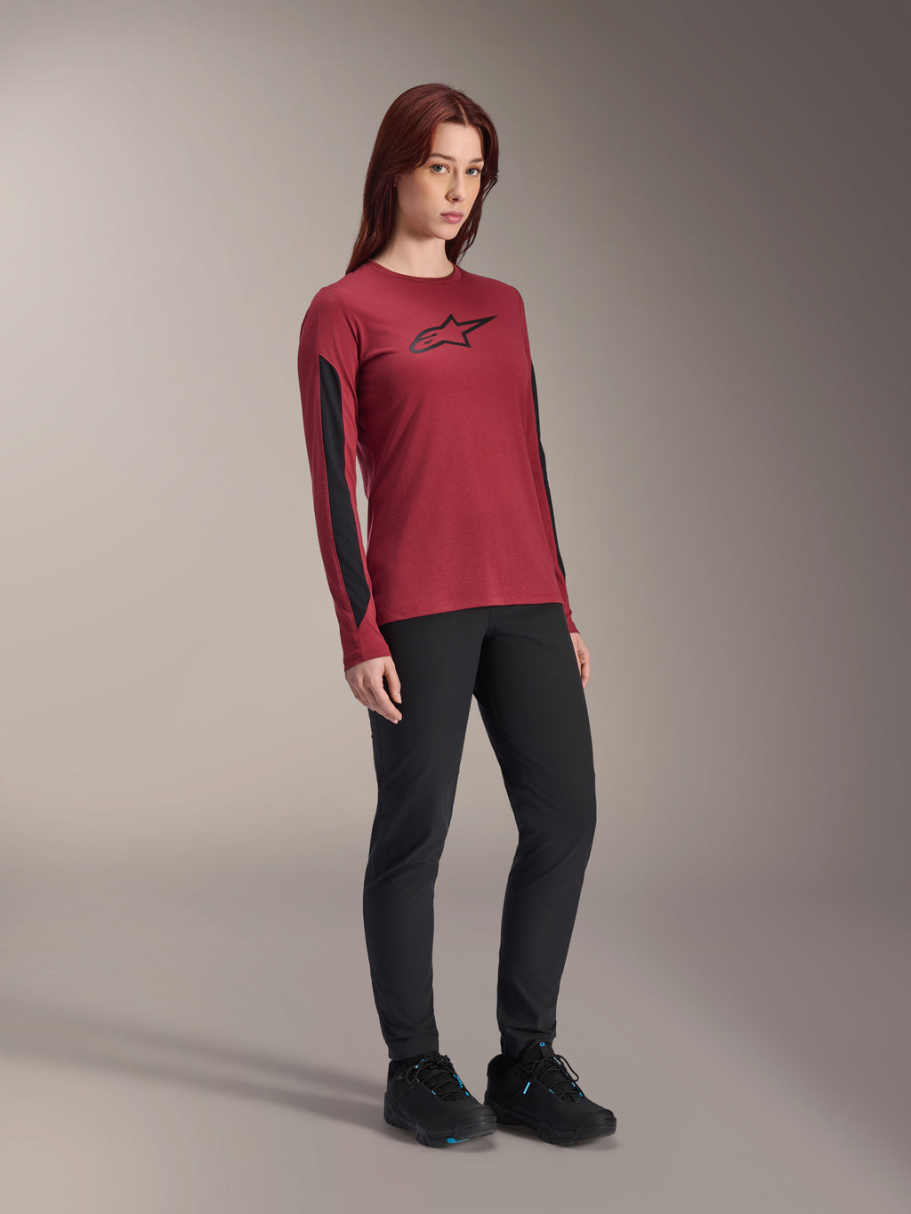 Camisola de Manga Comprida Alpinestars Stella A-Dura Dri Astar para Mulher, vermelho bordeaux com logótipo preto no peito e painéis de malha pretos nas mangas, usada com calças técnicas pretas e sapatos de ciclismo pretos, vestuário de BTT de alta performance para mulher